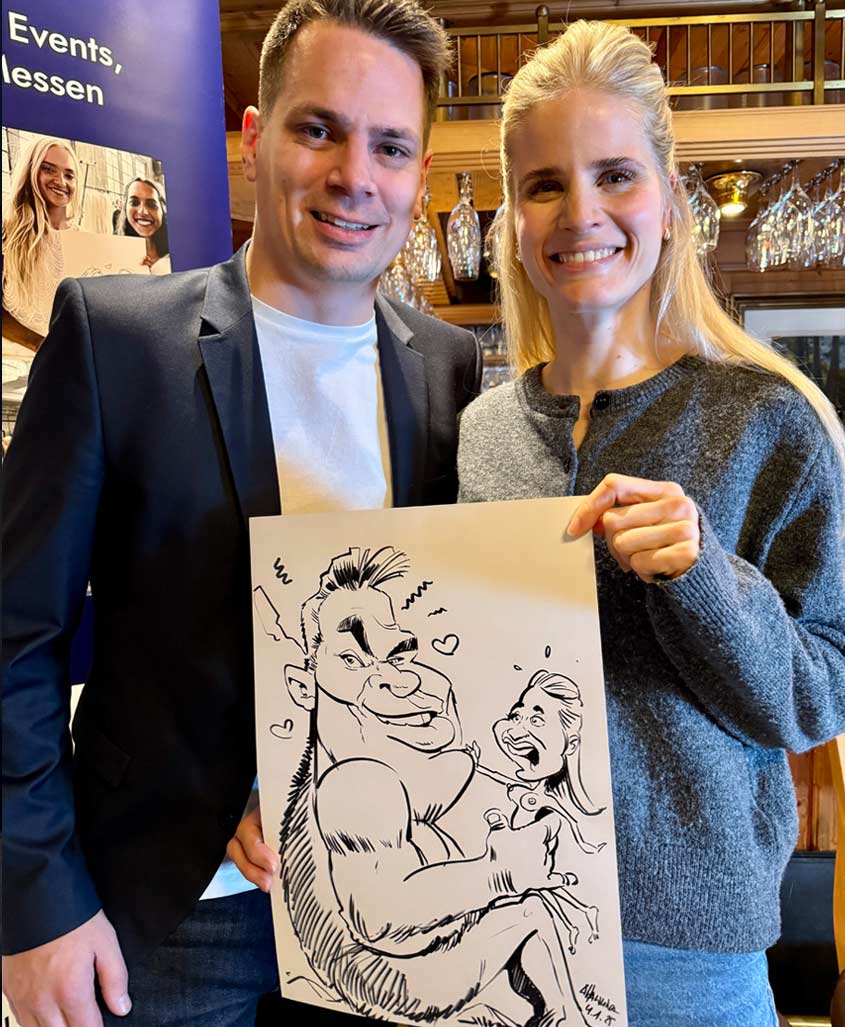 Ein Paar hält eine von Schnellzeichner Arnd Hawlina gezeichnete Karikatur in den Händen